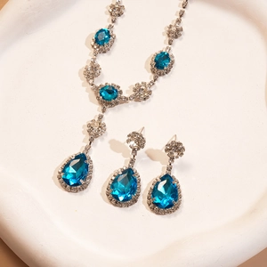 Gros plan sur un ensemble collier et boucles d'oreilles goutte bleu océan sur plateau