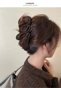 Close-up of a large matte dark brown wave claw clip styled on brunette hair