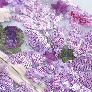 Macro shot of purple sequins, floral embroidery, and mesh fabric on a luxury dress