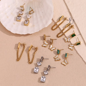 Flat lay of 18K gold plated earrings with zircon butterfly and geometric drops on shell
