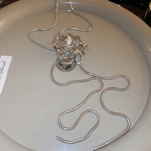Macro view of silver layered rose pendant with sleek metal snake chain on a tray