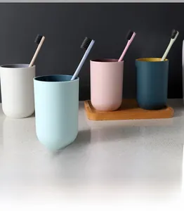 Minimalist two-tone plastic mouthwash cups in four colors on a textured stone surface