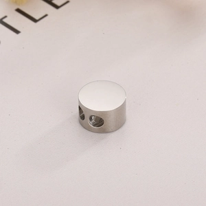 Polished silver stainless steel circular spacer bead with double holes on fabric background