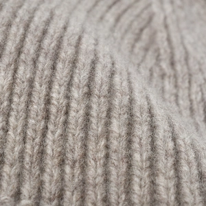 Close-up of thick taupe ribbed knit beanie made of warm wool with soft fluffy texture