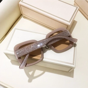 Detail of pink glitter square sunglasses with light brown lenses on a jewelry box