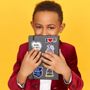 Detail shot of fantasy reading stickers on a black notebook held by a boy in velvet suit