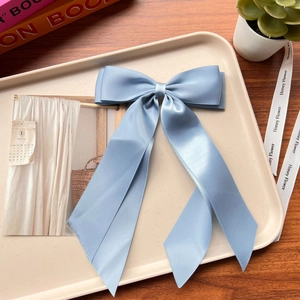 Detail of light blue satin double-layered bow hair clip with elegant long ribbons