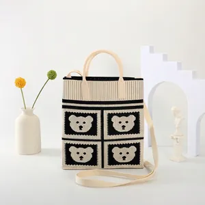 Detailed knit tote bag featuring bear patterns and cylindrical cream handles
