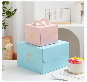 Detail of pink and blue paper cake boxes with gold foil text and clear window