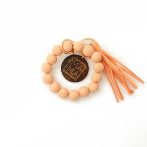 Gros plan du porte-clés en perles de bois léopard avec médaillon Mama et pompon rose