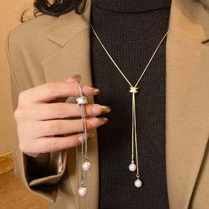 Détail d'un collier lasso en perles avec fermoir en zircon sur un col roulé noir élégant