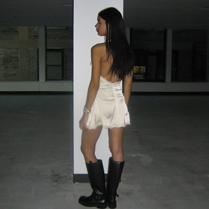 Back view of a white satin mini dress featuring backless design and delicate lace trim