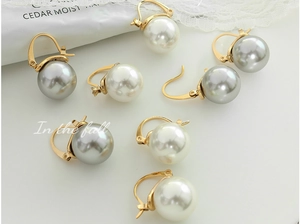 Détail de boucles d'oreilles perles or 18K avec perles blanches et grises sur dentelle