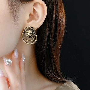 Gros plan d'une boucle d'oreille tête de lion dorée vintage portée par un mannequin