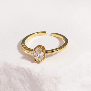 Detailed macro of gold adjustable ring featuring an oval zircon on a stone surface