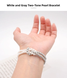 Close-up of three-strand knotted white and grey pearl bracelet on a wrist