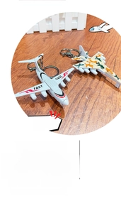 Detail of miniature fighter jet keychains with camo and white fast patterns on wood