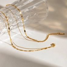 Detailed view of layered gold necklace featuring textured sequins and a lobster clasp closure