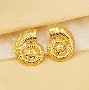 Dettaglio di orecchini a spirale in oro 18K su espositore in marmo bianco