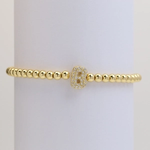 Detailed macro view of a gold beaded elastic bracelet with a zircon pavé letter B charm