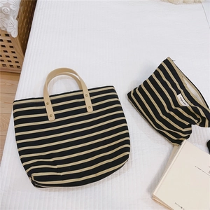 Detailed macro of striped canvas tote and matching zipper pouch with leather handles