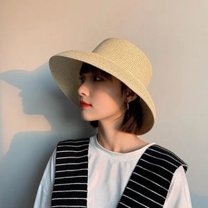 Artistic side view of a light beige straw sun hat with elegant woven texture on a model