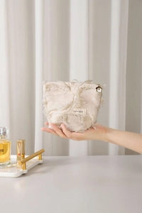 Close-up of linen cosmetic bag with fringe edges and flower zipper charm detail