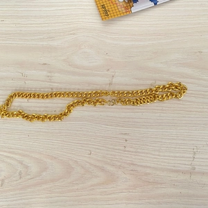 Flache vergoldete Kette mit S-Haken-Verschluss auf heller Holzmaserung-Oberfläche