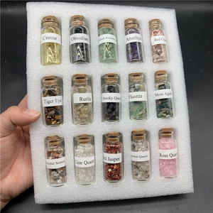 Set of 15 mini glass bottles with natural polished crystal chips on white foam tray