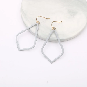 Detailed macro view of light blue hollowed-out teardrop earrings on marble tray