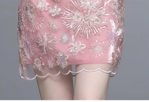 Détail de jupe rose brodée avec mesh floral, paillettes brillantes et bordure ondulée