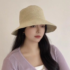 Detailed macro view of the fine hand-woven straw texture on a beige sun hat