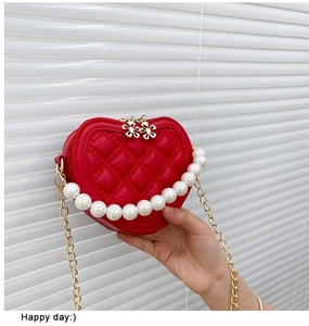 Detail of red quilted heart purse with pearl handle and golden chain for little girls