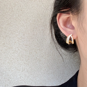 Golden woven hoop earrings with tiger eye stone and small zircons on female model