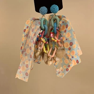 Detail of bridal floral tassel earrings with blue fabric bow and colorful bead accents