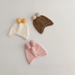 Three knit winter baby beanies with bow detail and ear flaps in white, brown and pink
