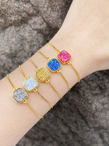 Detail shot of five colorful 18k gold plated bracelets with druzy square charms