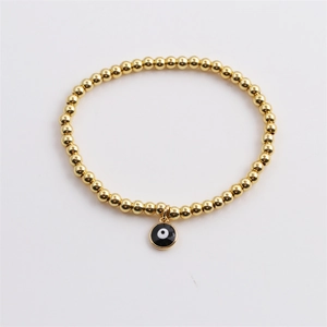 Minimalist gold plated beaded bracelet with a black and white evil eye charm on white background