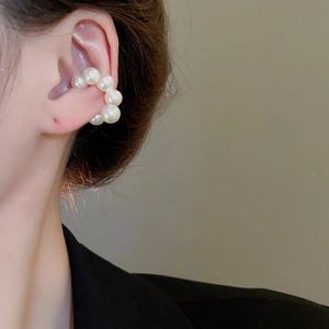 Dettaglio dell'orecchino a clip con perle a forma di C per un look elegante