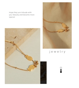 Detail view of two gold fish-shaped pendants and metal beads on a minimalist necklace