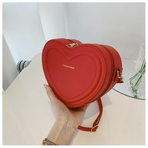 Dettaglio della borsa a tracolla rossa a forma di cuore con cerniera dorata e incisione