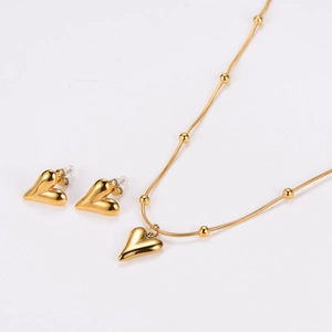 Macro shot of gold heart necklace and earring set featuring polished metallic finish