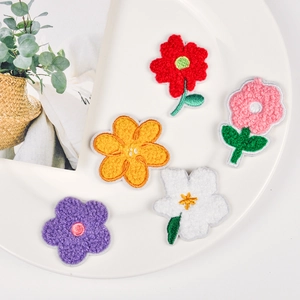 Colorful floral towel embroidery patches in five vibrant colors on a white ceramic plate