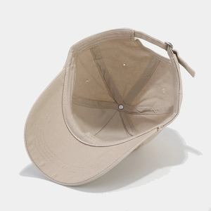 Inside view of beige cotton baseball cap with heart detail and adjustable metal buckle