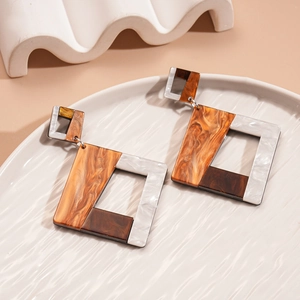 Macro view of geometric resin earrings with amber tortoiseshell patterns on a white plate