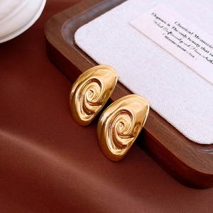 Detailed view of gold spiral flower earrings with polished metallic texture on velvet