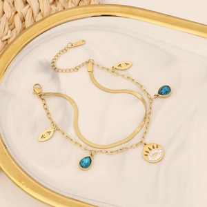Detailed close-up of a double-layer gold stainless steel bracelet with evil eye and charms