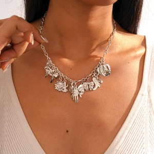 Detail of silver multi-pendant necklace with sun, boot and heart charms on model