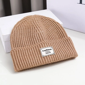 Winter knitted warm beanie hat in dark brown with confident label on a white gift box
