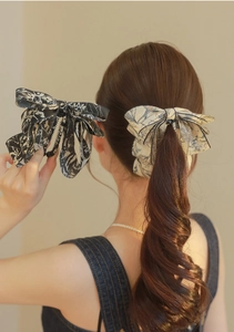 Detail of elegant ink-print fabric bow hair clips with a secure toothed banana clip design